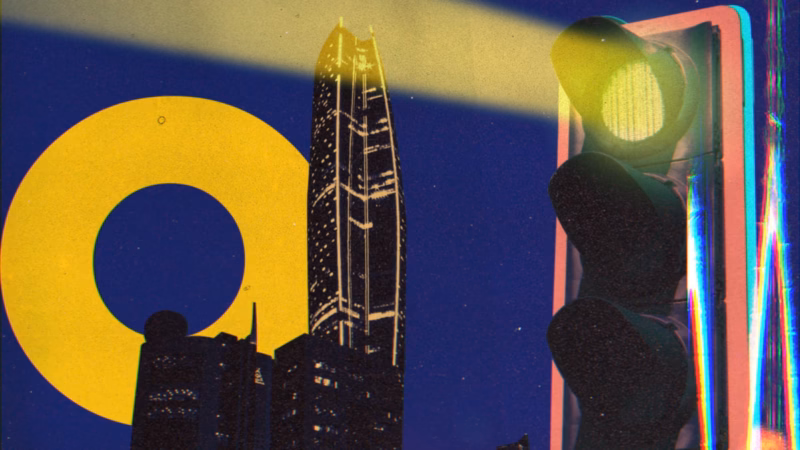 Illuminated skyscraper beside a traffic signal and a large yellow circle against a deep blue night sky.