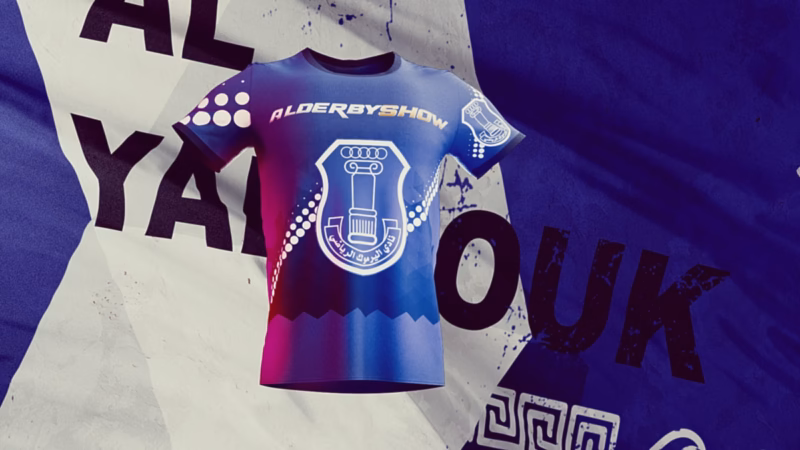 Blue Al-Yarmouk football shirt with the club crest and Al-Derby Show lettering against a fabric collage.