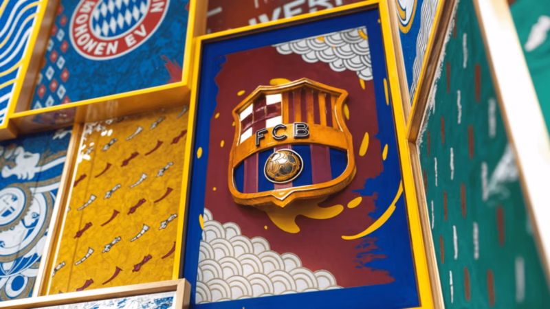 Gold-edged FC Barcelona crest on a patterned red and blue panel among framed club artwork for One Two.