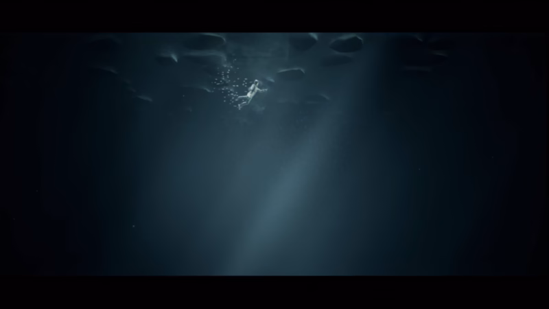 Ecliptica — a solitary figure floating underwater beneath shafts of light and rising bubbles